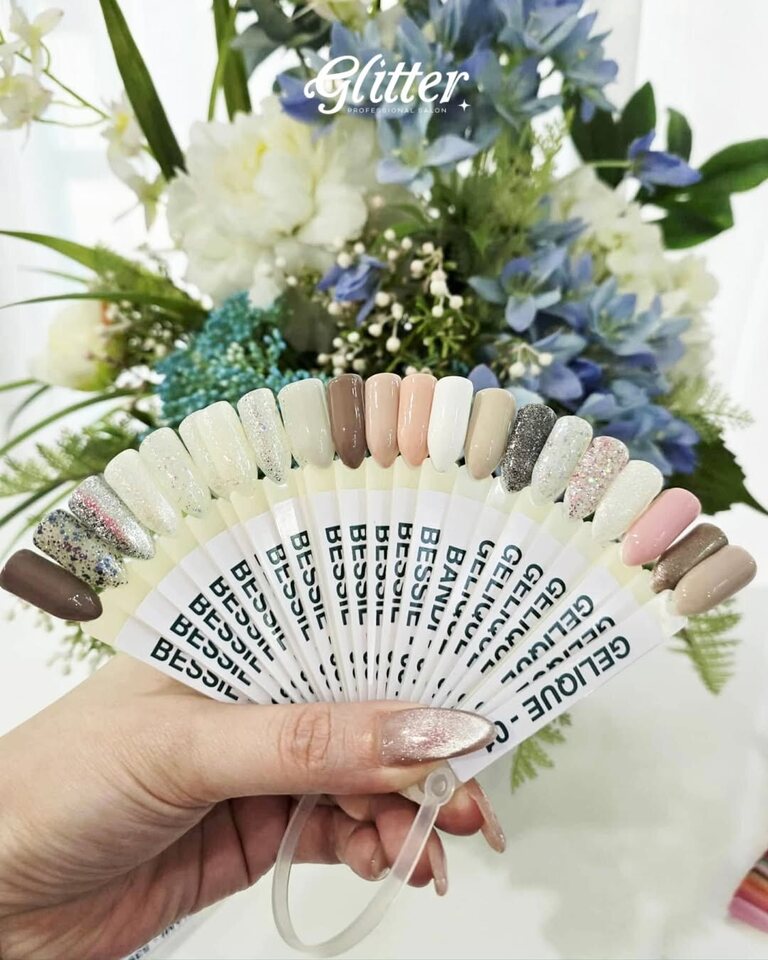 Glitter Professional Salon nail color swatches held in front of a floral arrangement